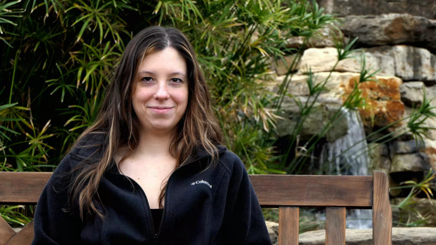 Cinemagraph of attractive millennial female on bench in front of small waterfall