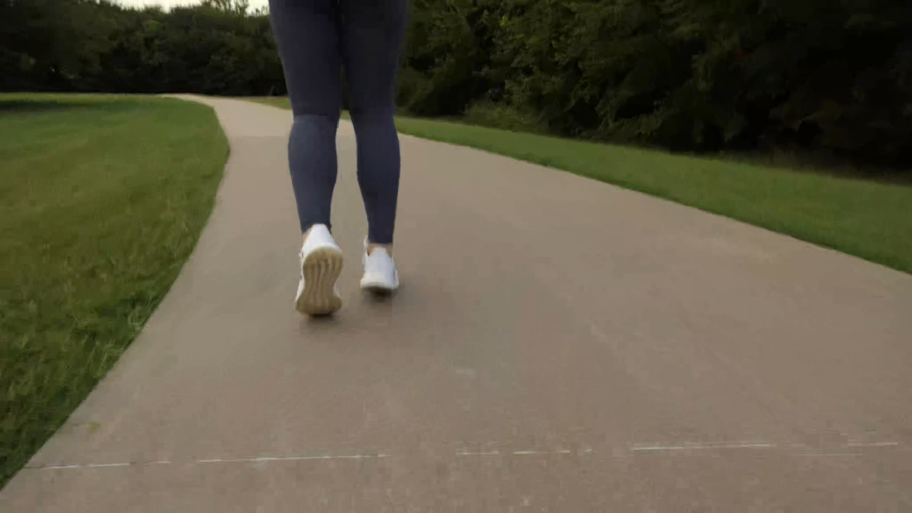 Low-level shot following behind the jogging feet of a young lady on a park path
