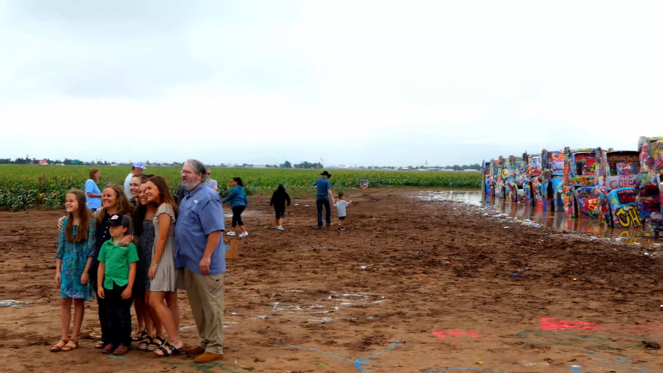 Families gather in the mud for photos and spray painting at the Cadillac Ranch