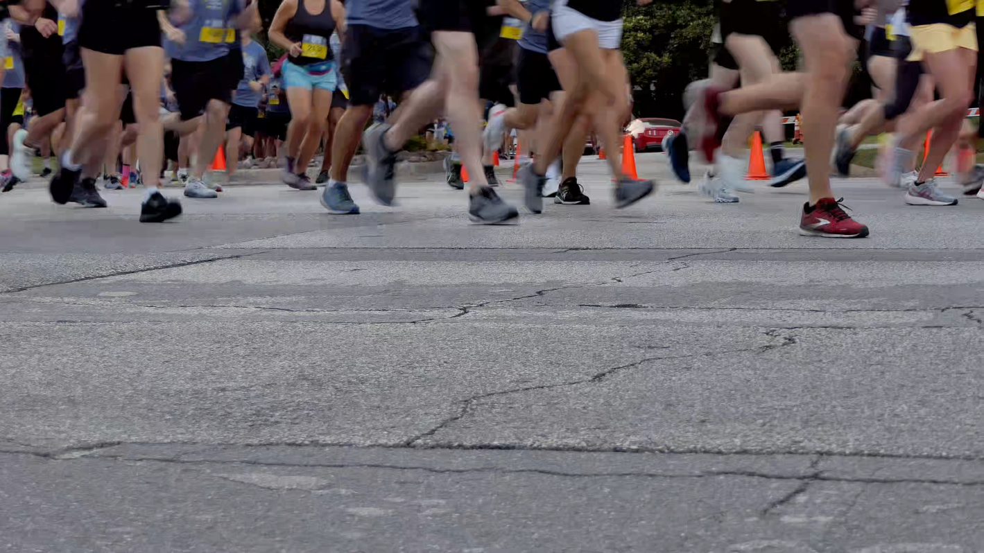 The pounding feet of a huge number of slower runners in a 5k run are passing by