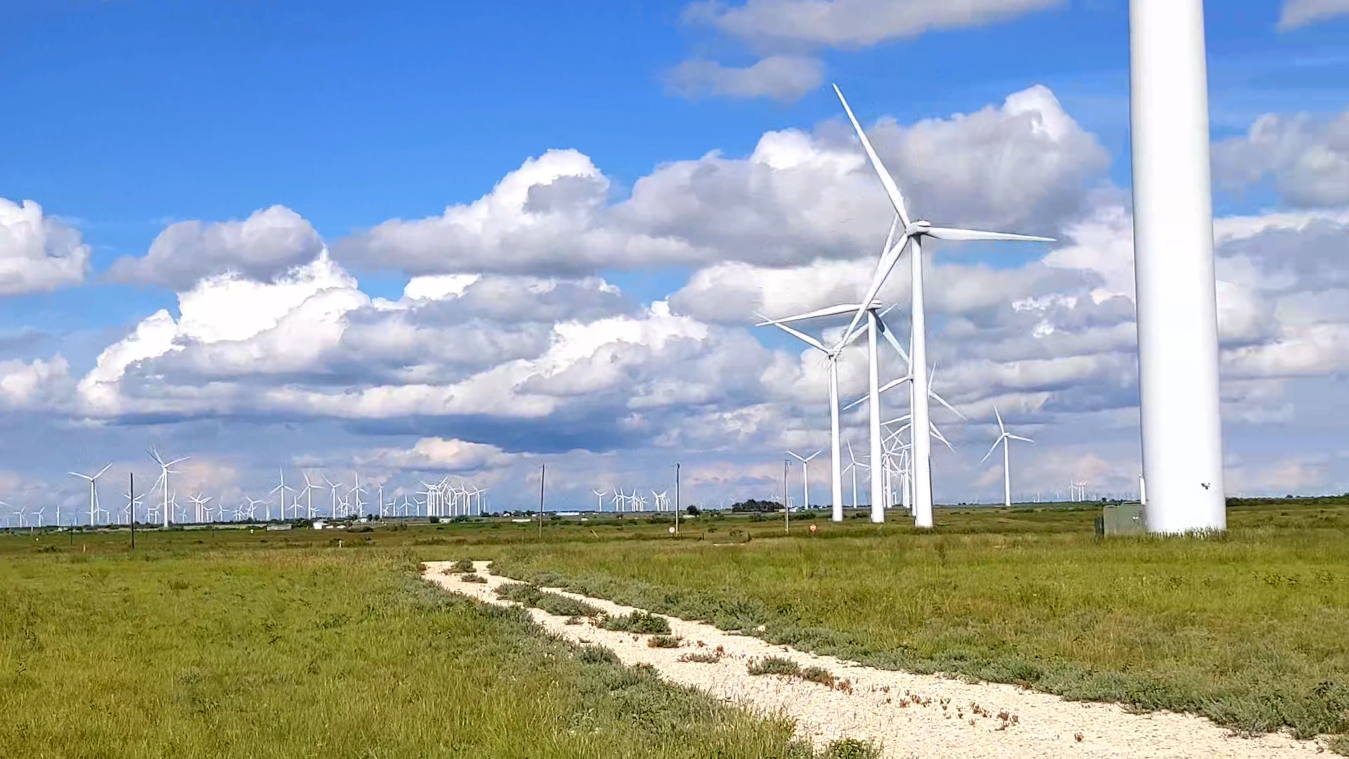 Pan across a vast section of Texas prairie showing scores of wind turbines